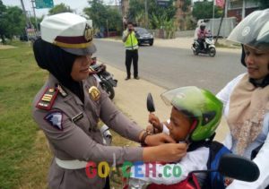 Kasat Lantas Polres Aceh Timur, AKP Nita Febrianti saat memasangkan helm kepada pengguna jalan dalam operasi Simpatik Rencong Bandar 2016. (Photo / GoAceh.co/ Asra)